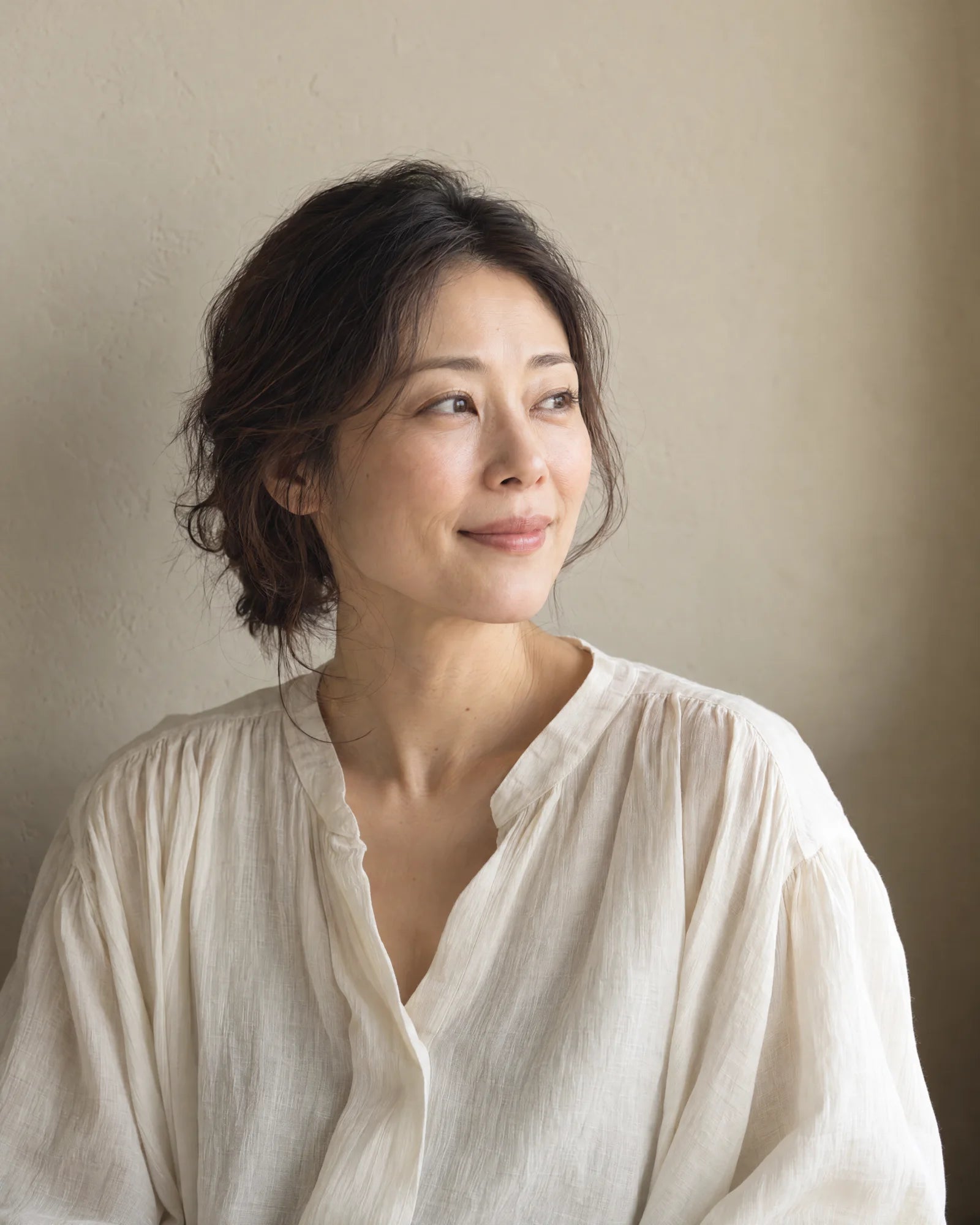 A woman resting her hand on her shoulder in natural light