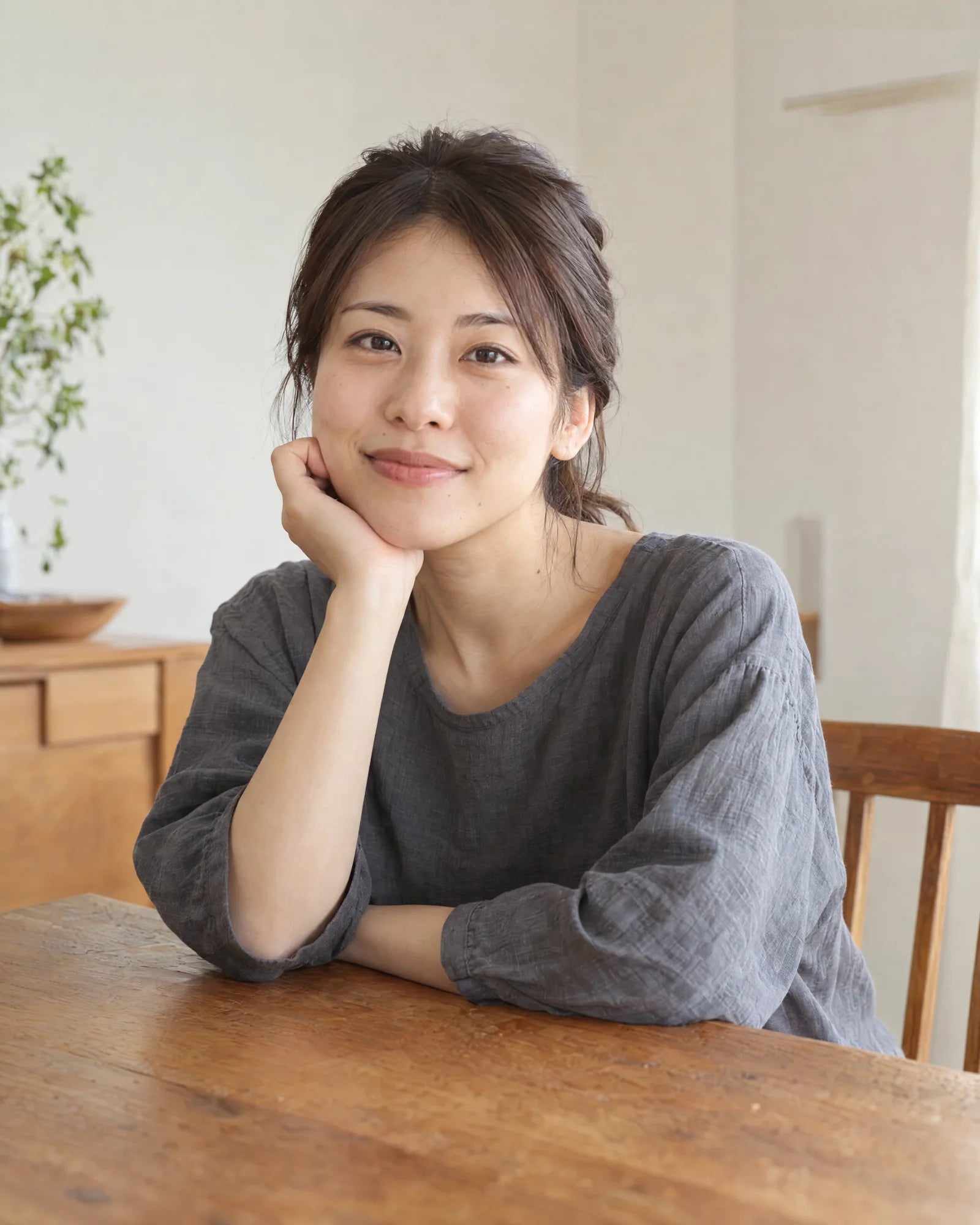 A woman in natural light resting her hand on her shoulder